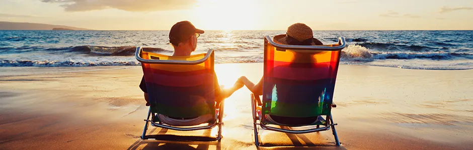 Two people relax in beach chairs on a sandy beach, enjoying the sun and ocean view.
